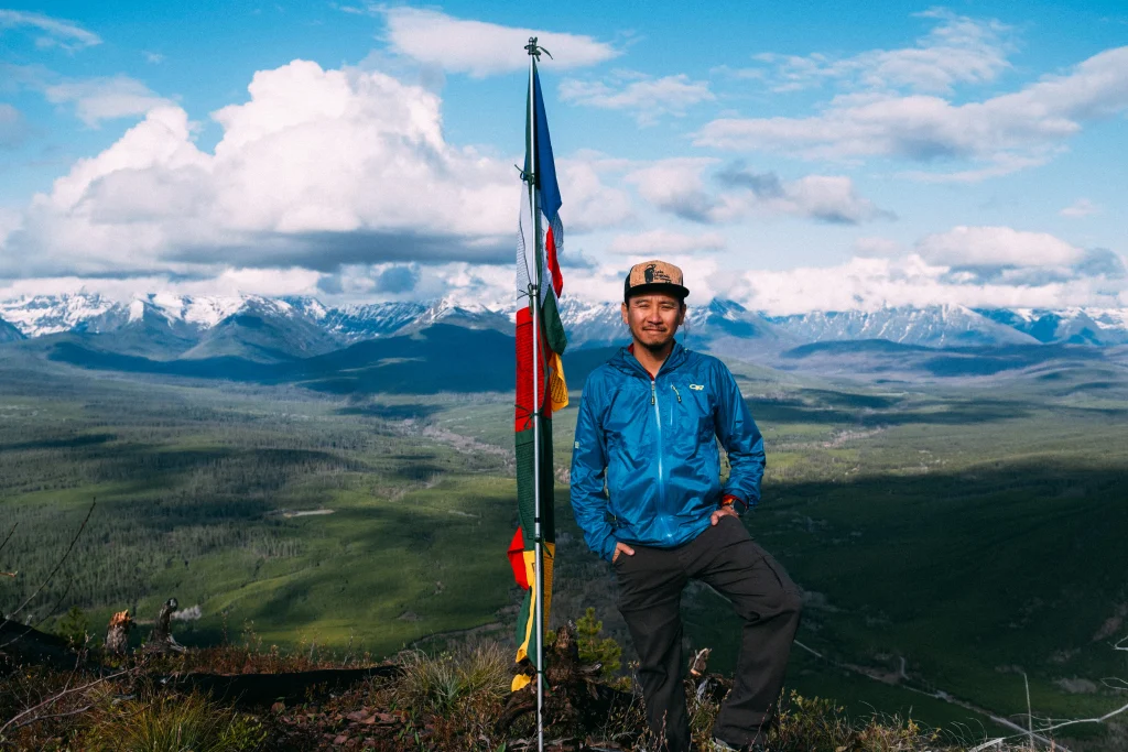 Jack Huynh standing beside prayer flags on a mountain ridge